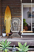 Surfbrett, Pfauensessel und Schaukel auf Vintage Veranda eines Holzhauses