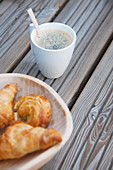 Cup of coffee and bowl of pastries on wooden boards