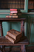 Antiquarian books on old wooden steps in front of bookcase