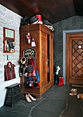 Coat rack on side of old wardrobe in foyer with stone floor