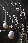 Easter eggs painted with stone effects and gold leaf hung from willow branches