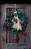 Festive wreath with tartan baubles and pine cones on wooden door
