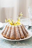 A whole bundt cake sprinkled with icing sugar with forsythia flowers