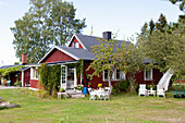 Falu-red Swedish house with seating areas in summery garden