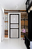 Panelled door in rustic wooden wall of simple hallway