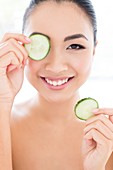 Woman holding cucumber in front of eye