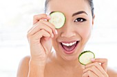 Woman holding cucumber in front of eye