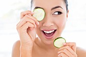 Woman holding cucumber in front of eye