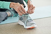 Senior woman lacing up trainers