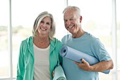 Senior couple holding yoga mats