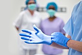Surgeon putting on latex glove