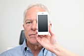 Man with smartphone covering eye