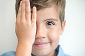 Boy covering one eye with hand
