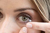 Mid adult woman putting contact lens in eye