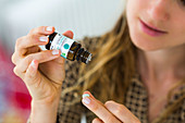 Woman applying essential oil on a neutral pill