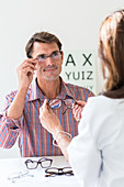 Man trying on prescription glasses in opticians