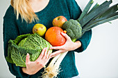 Woman holding fruits and vegetables in her arms