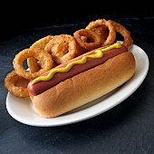 A hot dog with mustard and onion rings