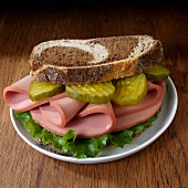 Bologna sandwich with lettuce and dill pickle on marble rye
