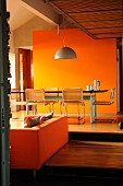 Esstisch vor orangefarbener Wand auf einer höheren Ebene