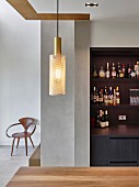 Drinks cabinet in open-plan kitchen, pendant lamp above dining table and designer chair in background
