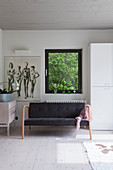 Black sofa below window with view of green plants