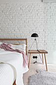 Simple wooden furniture in bedroom with white-painted brick wall