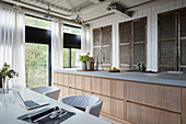 Large island counter in front of closed vintage louvre doors and dining table in loft apartment