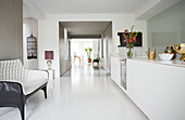 Sofa opposite white modern kitchen counter with long corridor in background