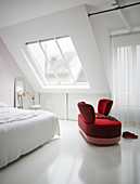 Red loveseat in white bedroom