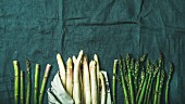 Fresh green and white asparagus in towel over dark grey linen table cloth background