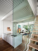 Glass wall in open-plan interior with island counter and floating staircase