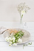 White ranunculus and gypsophila in stone bowl