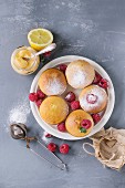 Homemade lemon muffin cupcakes with fresh raspberries, sugar powder, mint, served with jar of lemon curd and lemons