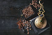 Roasted coffee beans and grind coffee in wood box with vintage coffee grinder and scoop over black wooden burnt background