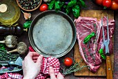 Raw T-Bone steak with a pan and various ingredients