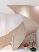 Designerstuhl und Rosen unter einer modernen geschwungenen Treppe