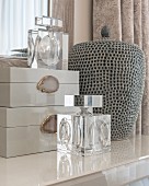 Elegant perfume bottles and boxes next to ceramic vase