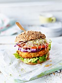 A veggie burger with sliced cabbage, lettuce, tomato and sprouts