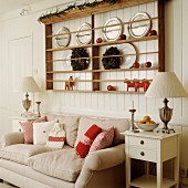 Plate rack on wood-clad wall above sofa with scatter cushions in shades of red