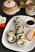 Maki sushi with soy sauce on a serving plate