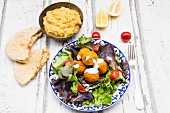 Falafel mit Joghurtsauce auf Blattsalat mit Hummus und Fladenbot
