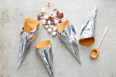 Eiswaffeln, Mini-Marshmalllows, Erdnusscreme und Schokoraspeln für Campfire-Cones