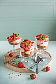 Strawberry and vanilla cheesecakes with a nutty biscuit base served in small glasses