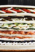 A mega sandwich with fruit, cheese, egg, salmon and pastrami