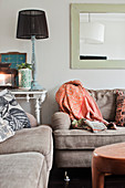 Scatter cushions and blanket on sofa set with table lamp on console table in background
