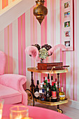 Old drinks trolley against stripes wallpaper in pink living room