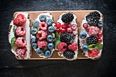 Bruschettas with berries and cream cheese on a wooden board