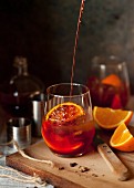 A Negroni cocktail being poured into a glass
