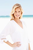 A blonde woman wearing a white tunic dress on the beach